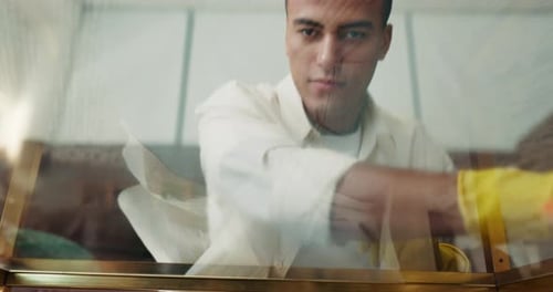 Smiling Young Adult Cleaning Glass Partition