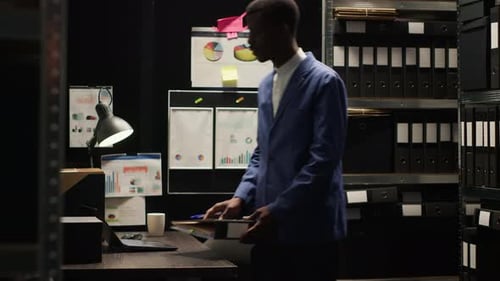 Man Consulting Files in Dim Office Setting