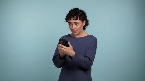 Surprised Woman Looking at Phone on Blue Background