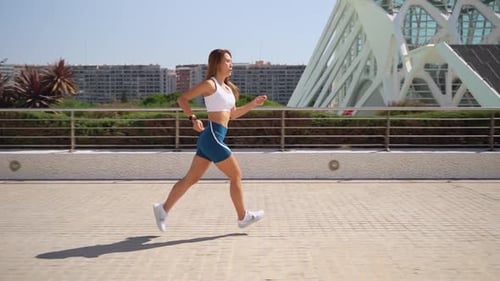Woman Running for Fitness in Sunny Urban Setting