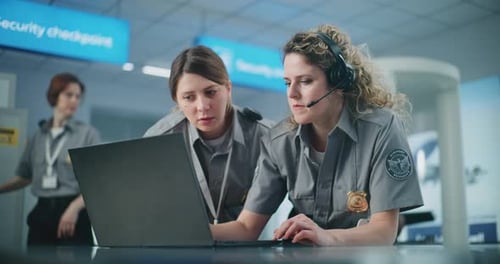 Airport Security Checkpoint Female Security Officer Wearing Headset Talks Uses Laptop with Colleague