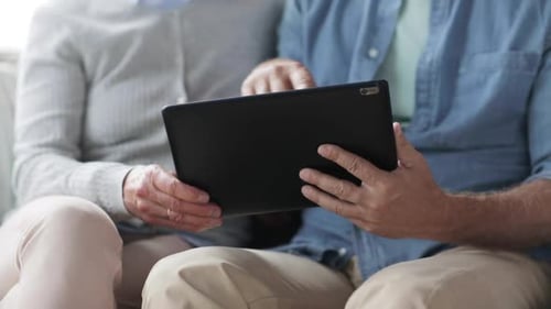 Mature couple using tablet at home, indoor scene