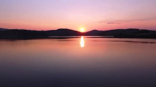 Couple kissing by the lake during beautiful sunset; aerial drone shot
