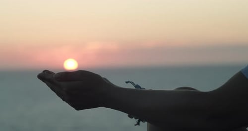 Mädchen, das bei Sonnenuntergang die Sonne in ihrer Handfläche hält. Traum- und Religionskonzept. Hand in der Sonne, Nahaufnahme