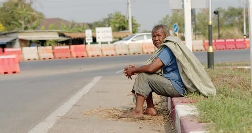An Asian man who is a poor ragpicker or collects garbage and sells, sitting on the side of the road