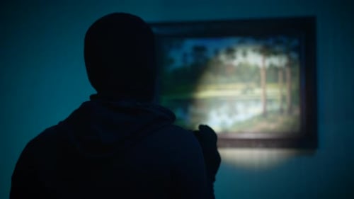 Person Wearing Head Covering Stands in Front of Painting