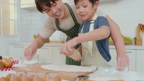 Boy and Man Rolling Dough in Bright Kitchen