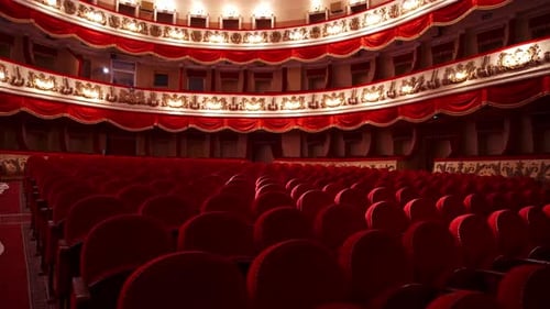 Beautiful theater in red colors indoors. Spacious hall with vacant seats in opera house.