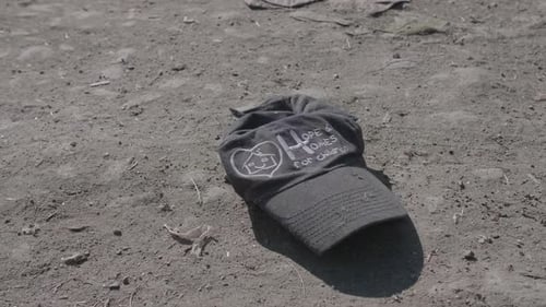 Discarded 'Hope & Homes for Children' Charity Hat Lying in the Dirt