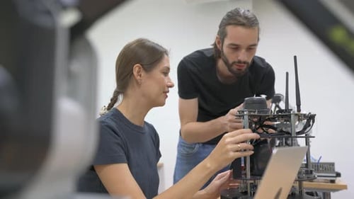 Caucasian professional technician man and woman worker check and discuss together about small robot