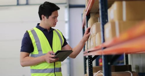 Mann arbeitet im Auslieferungslager mit digitalem Tablet