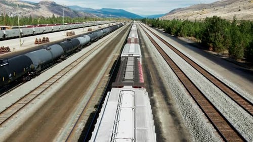 forward flight dolly drone shot flying over a cargo train on a railroad station in a desert environm