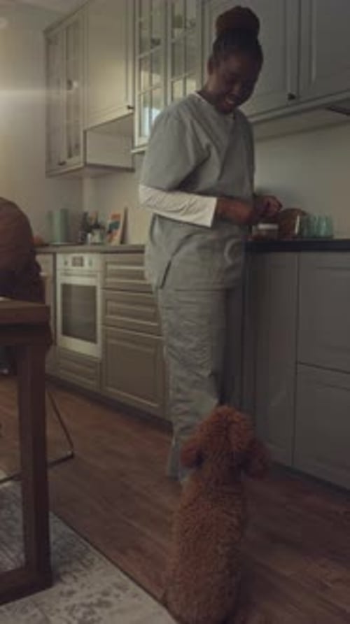 Smiling Woman Petting Small Dog in Kitchen