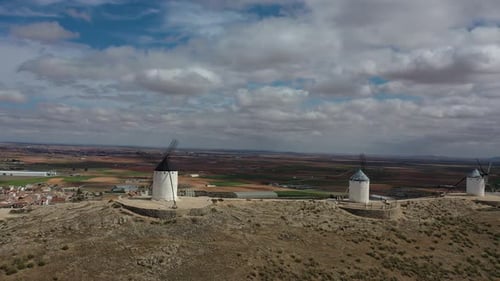 lateral flight with a drone on a hill visualizing three old windmills being visited by people with a