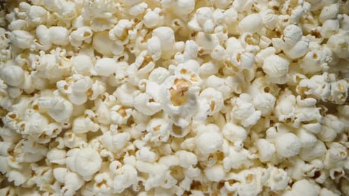 The whole frame is filled with popcorn, One grain in the middle rotates, a close-up view from above.