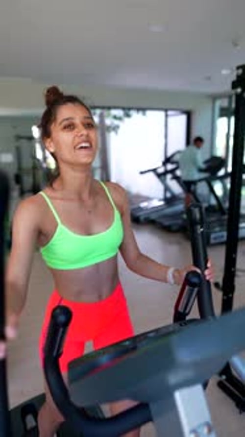 Young Woman is Energetically Working Out on an Elliptical Machine in a Modern Fitness Center