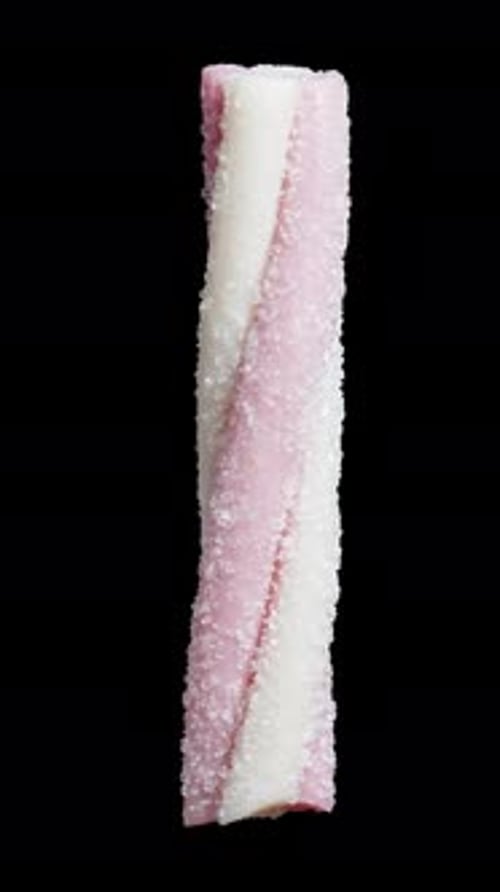 Vertical. gummy candy in the shape of a twisted pink stick, dusted with sugar. It rotates on a black