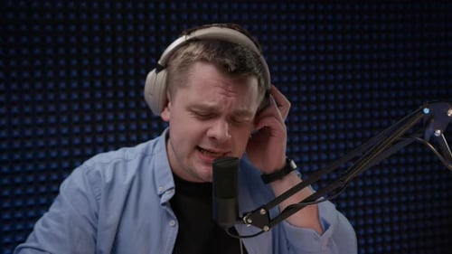 Handsome Man in Headphones in Blue Shirt Singing in Recording Studio Professional Singer or Radio