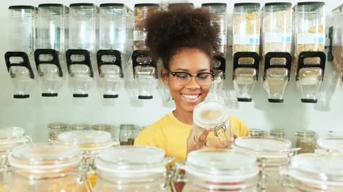 A young woman shopped in refill store, reusable jars, and zero-waste groceries.