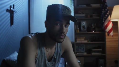 Young Adult Man Sits in Dimly Lit Room