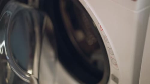 Closeup of Hand Opening Modern Washing Machine in Store