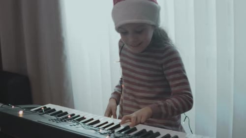 Petite fille jouant du piano électrique lors d'une fête de Noël à la maison Anamorphic Lens Flare