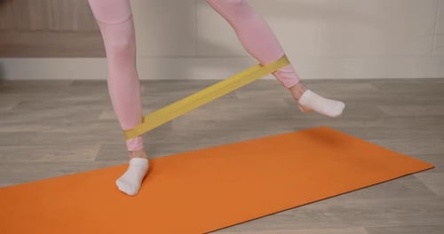 Woman Exercising Legs with Resistance Band on Yoga Mat