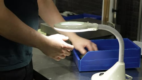 Travailleur inspectant des capsules de bouteilles fabriquées à la loupe