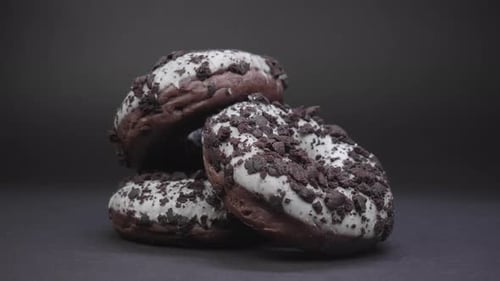 Dark chocolate donuts with white topping filmed in studio close-up