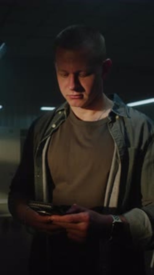 Young Man Checking Fitness App on Smartphone in Gym Locker Room Before Workout