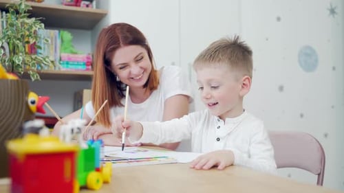 Glückliche Familie. Mama und hübscher Sohn zeichnen in aller Ruhe zu Hause an einem Tisch.
Mutter