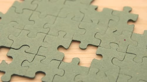 Close up of a young girl's hand putting a puzzle piece in the last blank spot concluding a single co