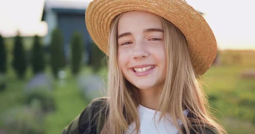 Portrait d'une petite jardinière au chapeau regardant la caméra tenant une boîte de fleurs.
Fleurs