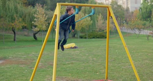 Boy Swinging on Swing Child Having Fun Playing in Outdoor Public Playground