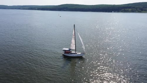 Aerial View of Several Sailboats Moving Across a Calm Lake Under Clear Blue Sky Yachts Floating