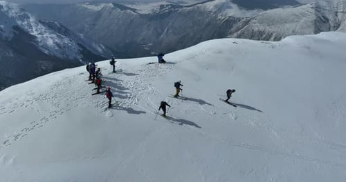 Cinematic Aerial Epic Scene of Group of Skiers and Snowboarders on Top of a Mountain