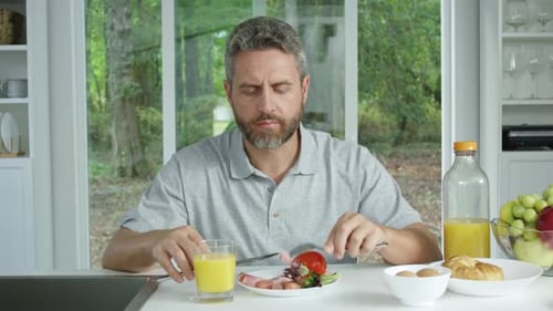 Man eating breakfast in sunny kitchen at home