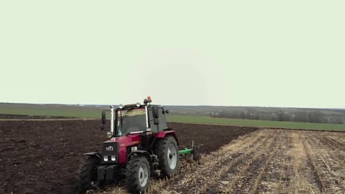 Red tractor plowing the field in Ukraine