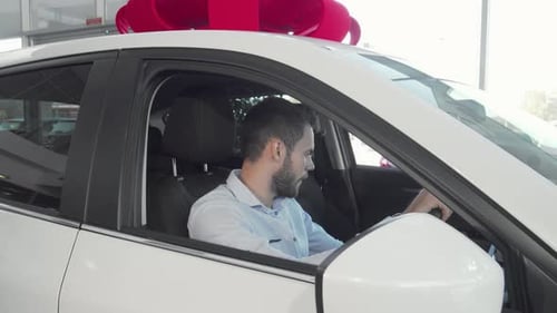 Cheerful Man Proudly Displaying Car Keys in His New Vehicle at the Dealership