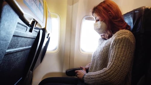 Woman wearing face mask sitting in airplane