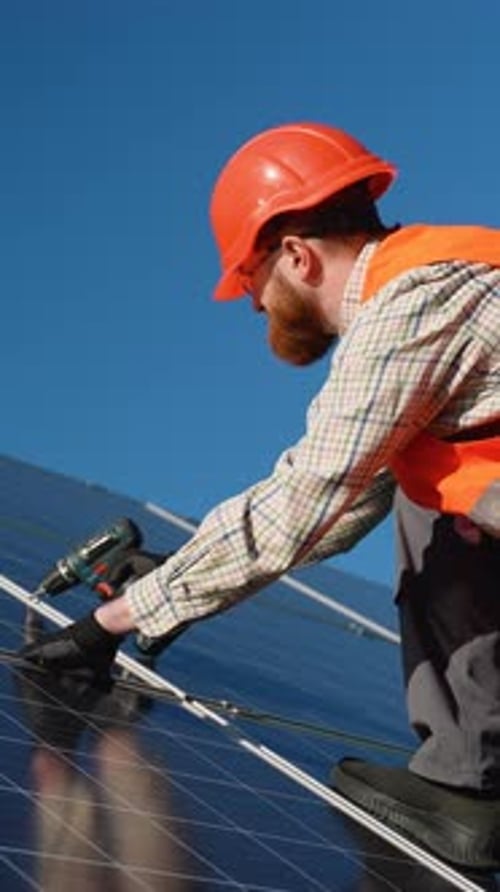 Irish Technician Installing Solar Panels on Rooftop Under Blue Sky