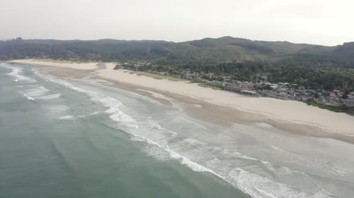 Drone shot of hotels and houses on the West Coast with forest and ocean.