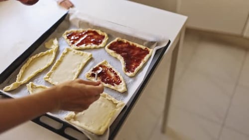 Pastry Chef Spreading Jam on Raw Dough Pieces