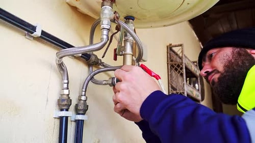 medium shot of a plumber observing and fixing an electric water heater