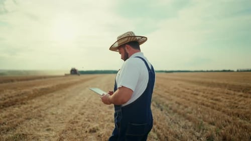 Farmer Uses Tablet in Harvested Wheat Field