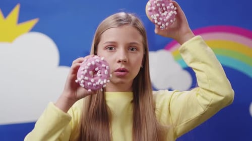 A Joyful Girl Holding Sweet Doughnuts Beneath a Beautiful Rainbow in the Sky Above