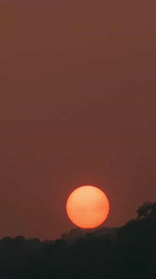 Zeitraffer eines dramatisch Sonnenuntergangs mit orangefarbenem Himmel an einem sonnigen Tag.