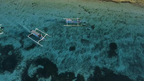 Fishing boat is sailing in blue ocean on Bali island. Aerial view.