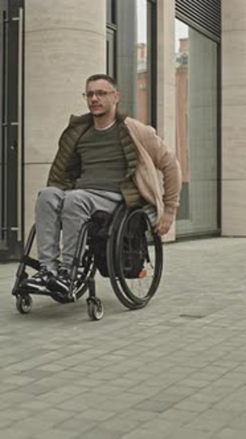 Man Riding Wheelchair along City Street