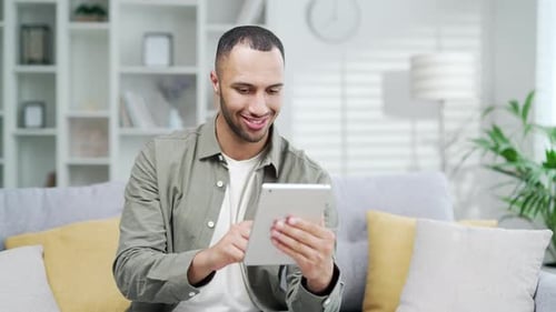 Young adult man using digital tablet while sitting at home office in living room Happy Male guy